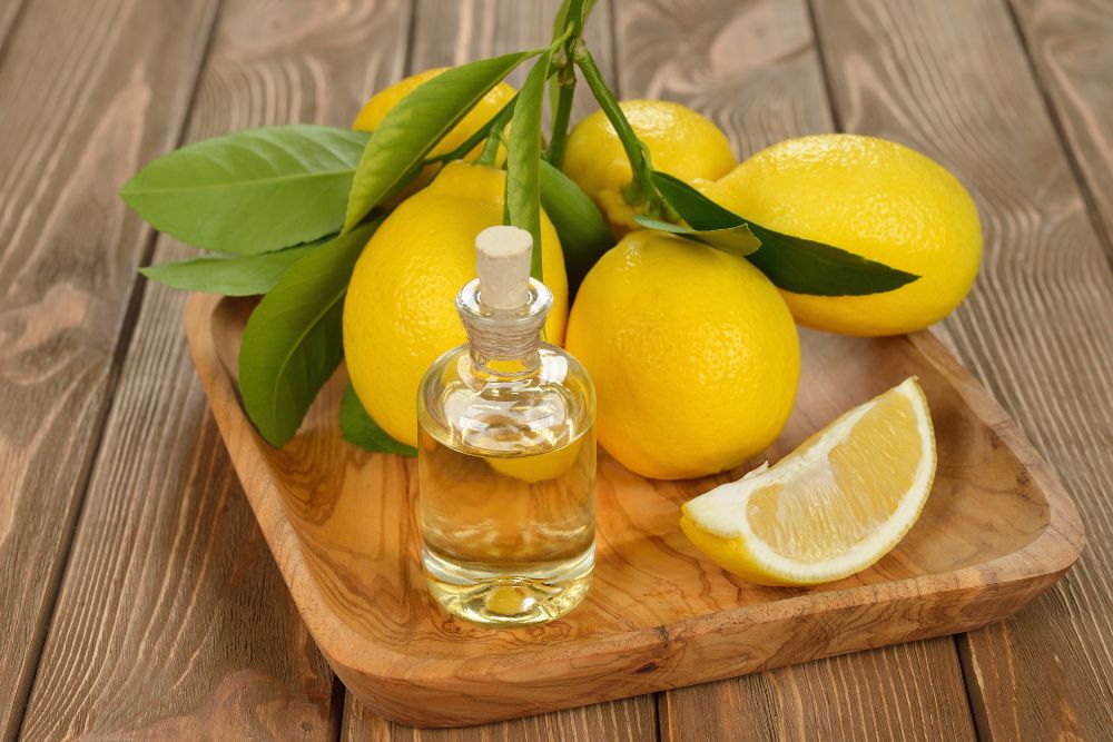 Citrónový olej v malej fľaštičke s čerstvými citrónmi na drevenom podklade